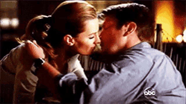 a man and a woman are kissing each other in a room .
