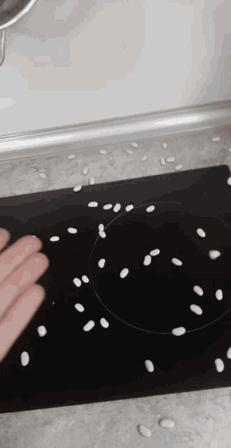 a person 's hand is reaching out towards a circle of white beans