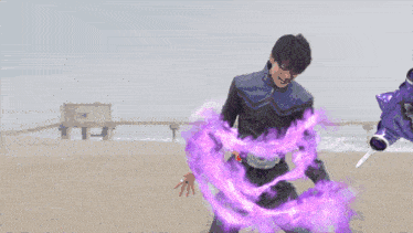 a man is standing on a beach with purple flames coming out of his hand