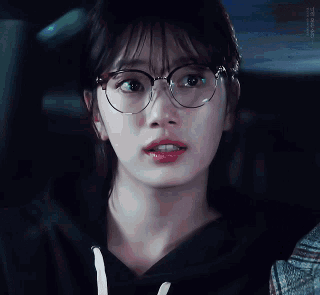 a close up of a woman wearing glasses and a black sweatshirt