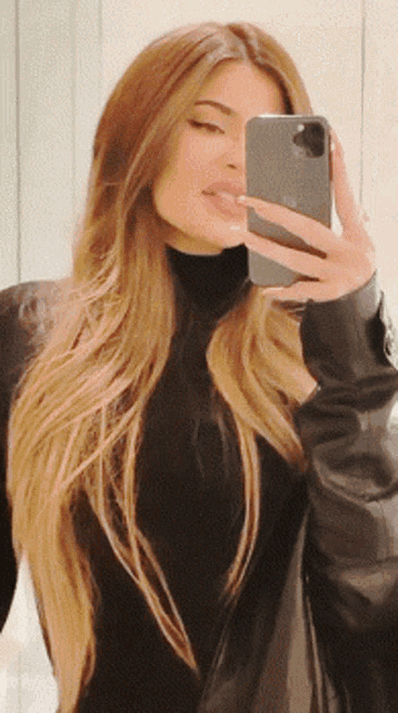 a woman taking a picture of herself with her iphone