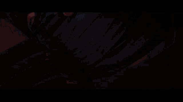 a woman with blue hair is standing in a dark room with the letter v visible