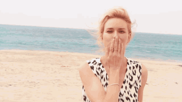 a woman wearing a leopard print top is smiling on the beach