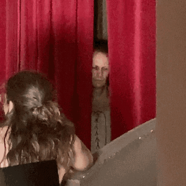 a man behind a red curtain with a woman behind it