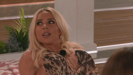 a woman in a leopard print dress is sitting on a bed and talking to a man .