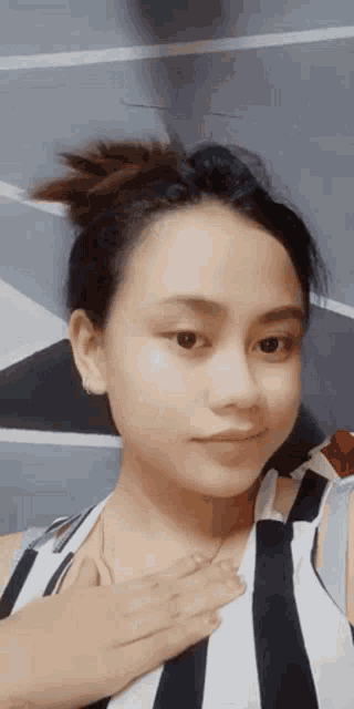 a woman in a black and white striped shirt has her hand on her chest .