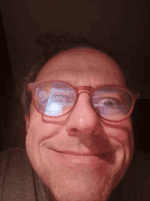a man wearing red glasses is smiling and making a face