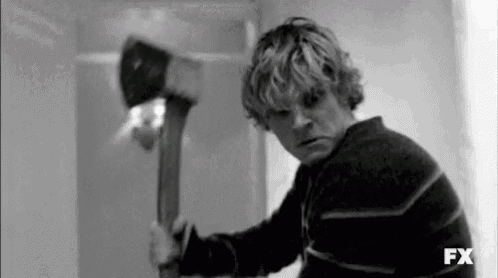 a black and white photo of a man holding an axe in a room .