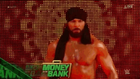 a shirtless wrestler with long hair and a beard is standing in front of a red and green background .