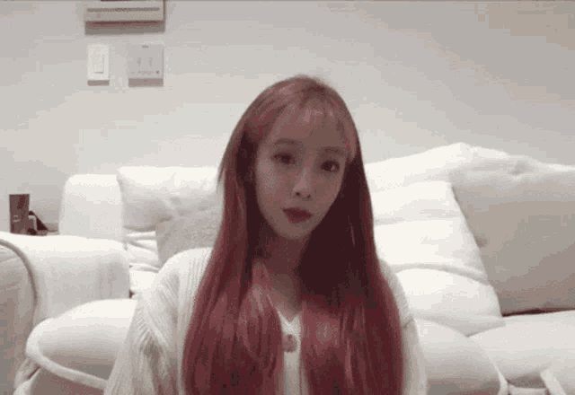 a girl with red hair is sitting on a white couch .