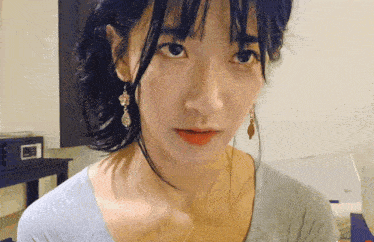 a close up of a woman wearing earrings and a gray shirt