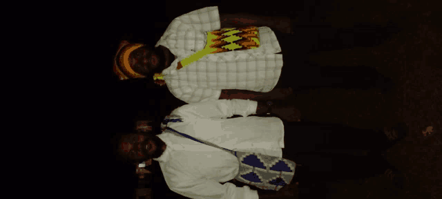 two men standing next to each other with one wearing a plaid shirt with a yellow flame on the front