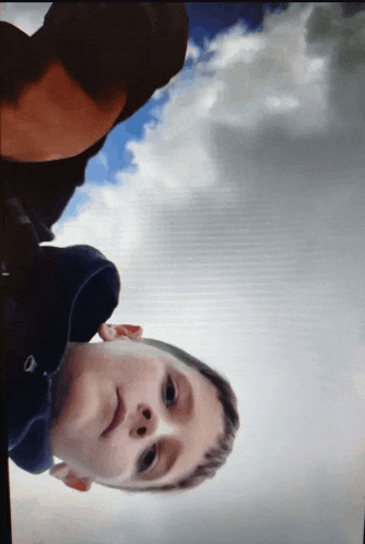 a man and a boy are looking up at the sky with clouds