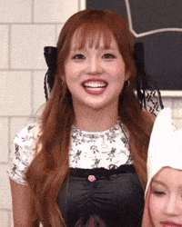 a woman with red hair is smiling while wearing a white shirt and a black apron .