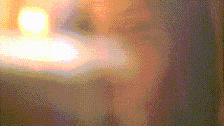 a blurred image of a person 's face with a candle in the background