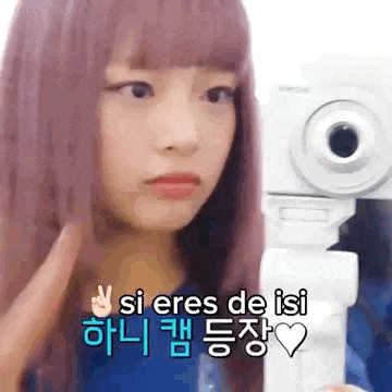 a girl with pink hair is taking a picture of herself with a white camera .