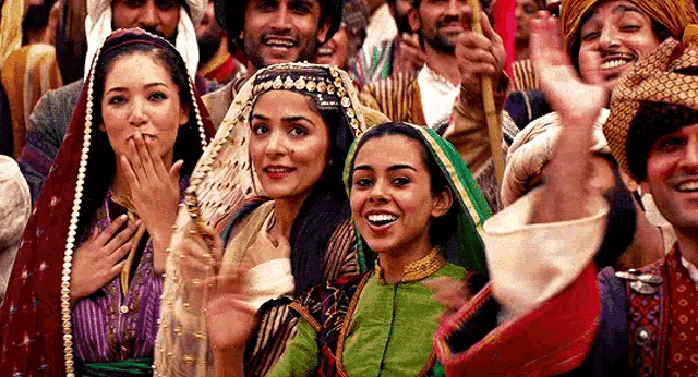 a group of people in traditional costumes are standing in a crowd and laughing .