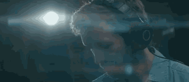 a man with a beard is wearing headphones and playing a guitar in a dark room .
