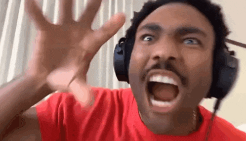 a man wearing headphones and a red shirt is making a funny face with his mouth open .