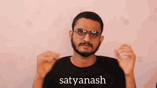 a man wearing glasses and a black shirt with the name satyanash on it