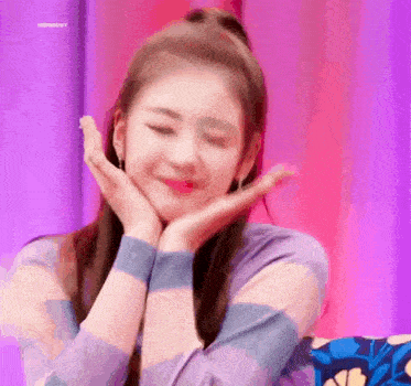 a close up of a woman holding her face with her hands and smiling .