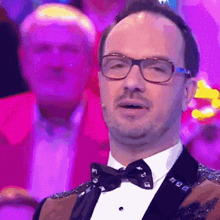 a man in a tuxedo and bow tie is making a face .