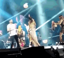 a group of people are dancing on a stage in front of a spotlight
