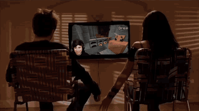 a man and a woman are holding hands while looking at a screen that says dream
