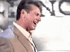 a man in a suit is laughing with his eyes closed .