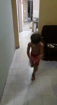 a little boy in red shorts is running down a hallway towards a couch