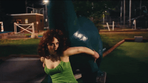 a woman in a green dress is sitting on a ledge