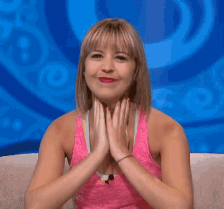 a woman is sitting on a couch with her hands folded in front of her face .