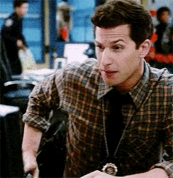a man in a plaid shirt and tie is sitting at a table in a room .