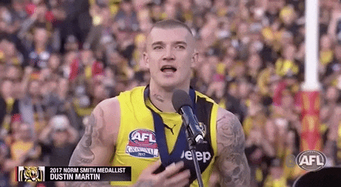 a man in a yellow shirt is standing in front of a microphone and talking into it .
