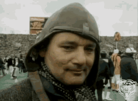 a man wearing a helmet and scarf stands in front of a crowd of people