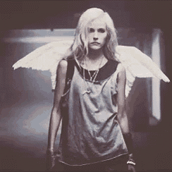 a woman wearing angel wings is standing in a dark hallway