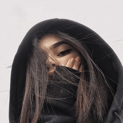 a woman wearing a black hoodie covering her face