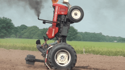 a red farmall tractor is upside down on a dirt field