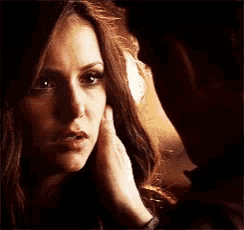 a man is touching a woman 's face while they are looking at each other .