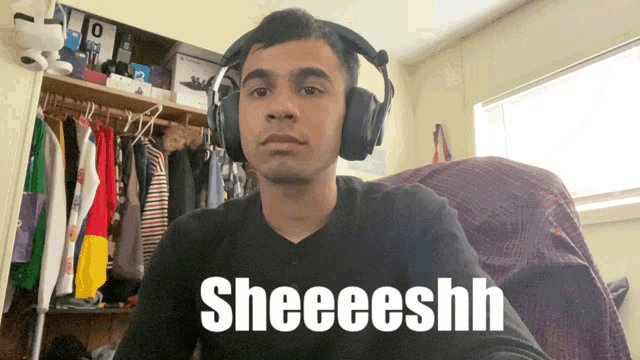 a man wearing headphones says sheeeeshh in front of a closet full of clothes