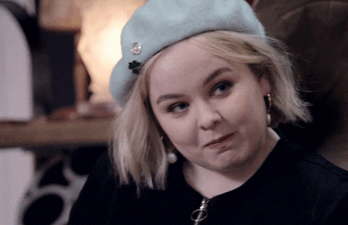 a blonde woman wearing a blue beret with a shamrock on it