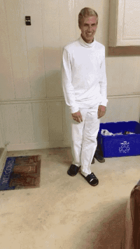 a man standing in front of a blue recycling bin