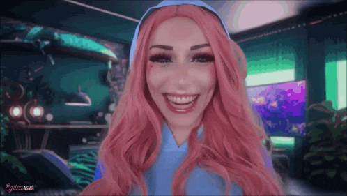 a woman with pink hair is smiling and wearing a blue dress
