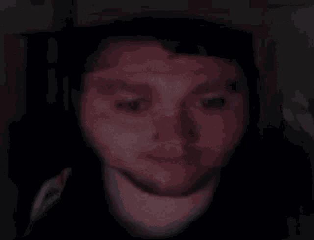 a man wearing headphones is pointing at the camera in the dark .