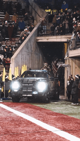 a black shelby truck is driving down the field