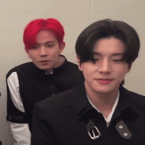 a man with red hair is standing next to another man in a black jacket