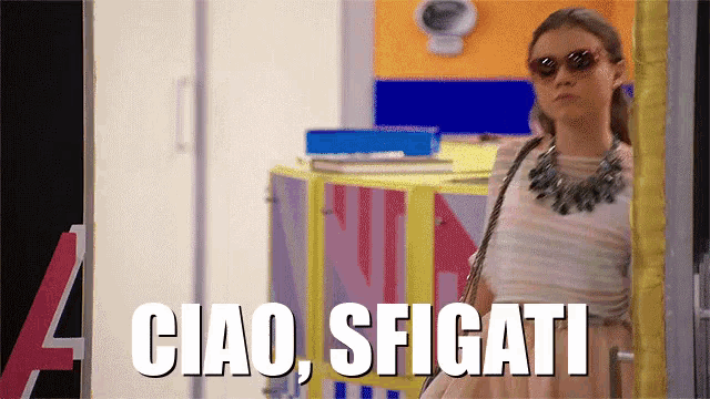 a woman wearing sunglasses is standing in front of a sign that says " ciao sfigati "