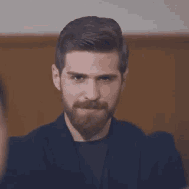 a man with a beard and mustache is making a funny face while looking at the camera .