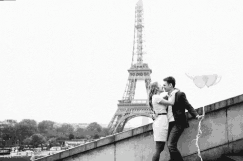 a man and woman are kissing in front of the eiffel tower in paris .