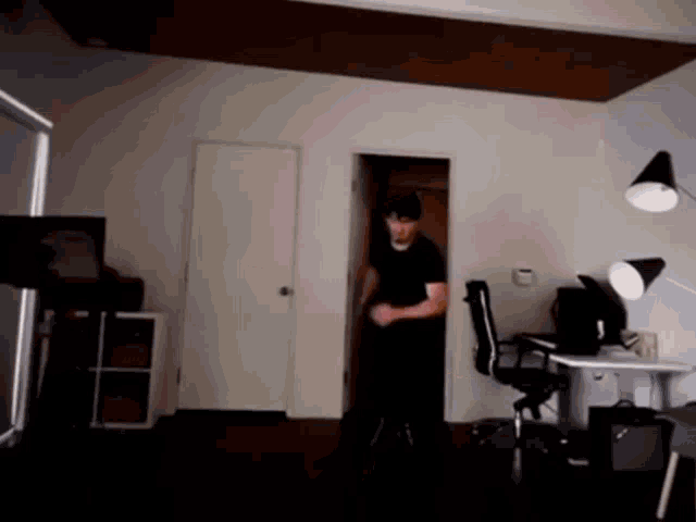 a man in a black shirt is walking through a doorway